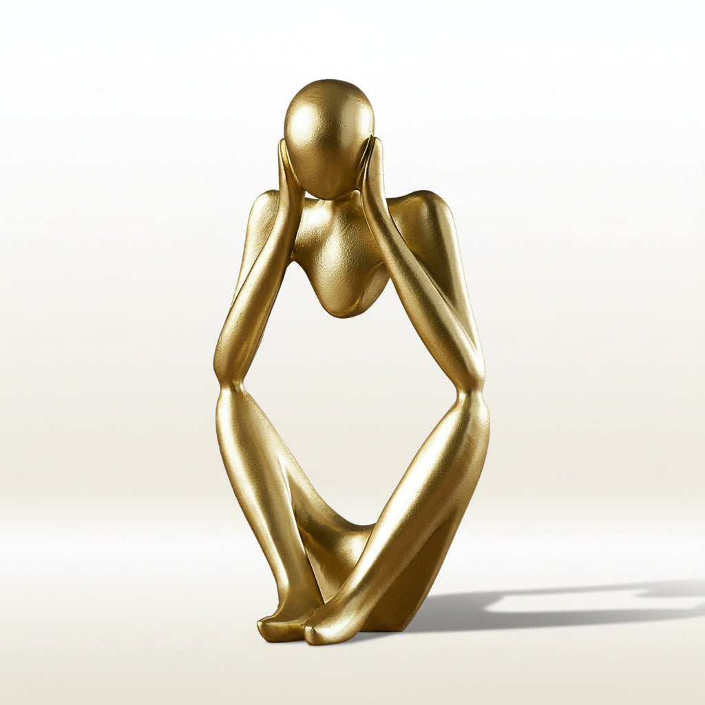 Gold sculpture of a figure with hands over ears on a white background