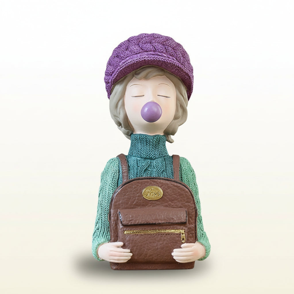 Decorative figurine of a person wearing a purple knitted hat and green sweater, holding a brown backpack with a gold emblem on a gray background.