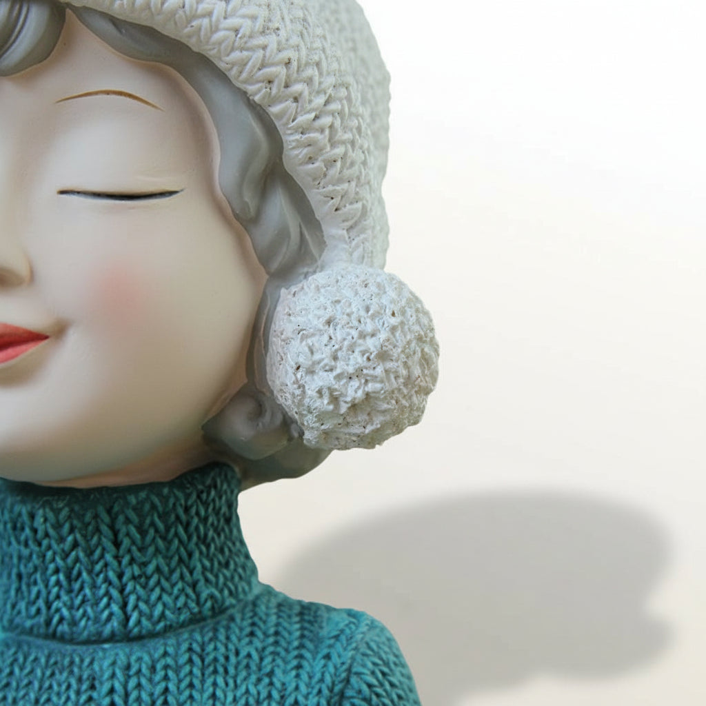 Close-up of a figurine with a textured headpiece and green garment against a gray background 